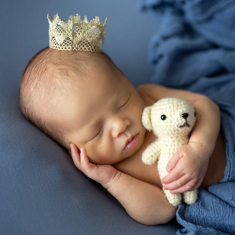 レンタル＆フォトスタジオの光翔　鉾田市　babyのギャラリー　青地の背景で、冠を載せてぬいぐるみを抱っこしたニューボーンの赤ちゃん