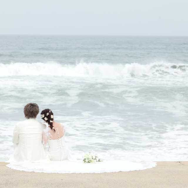 レンタル＆フォトスタジオの光翔　海辺に座ったご新郎様ご新婦様の後姿
